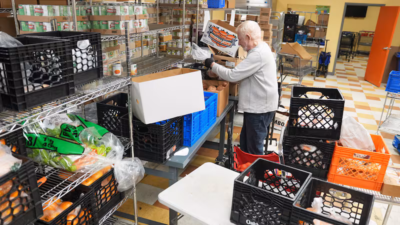 Volunteer Bruce Toben packs groceries durning an emergency food distribution at the at The...